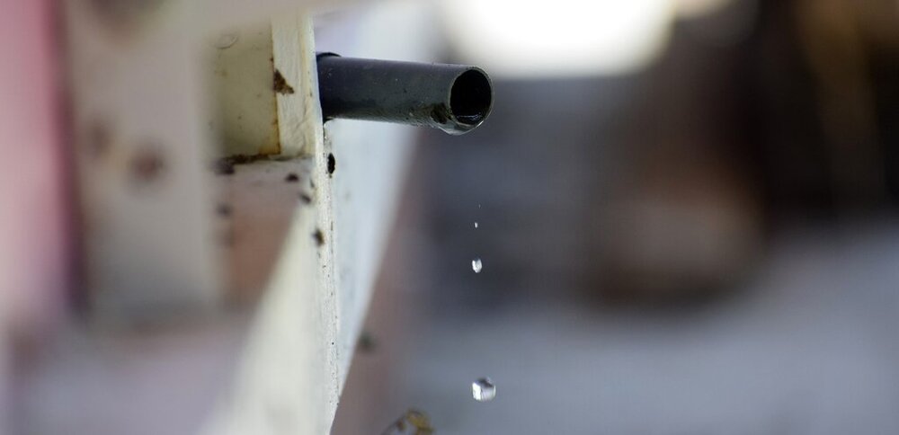 Water drops flowing out of a leaking pipe